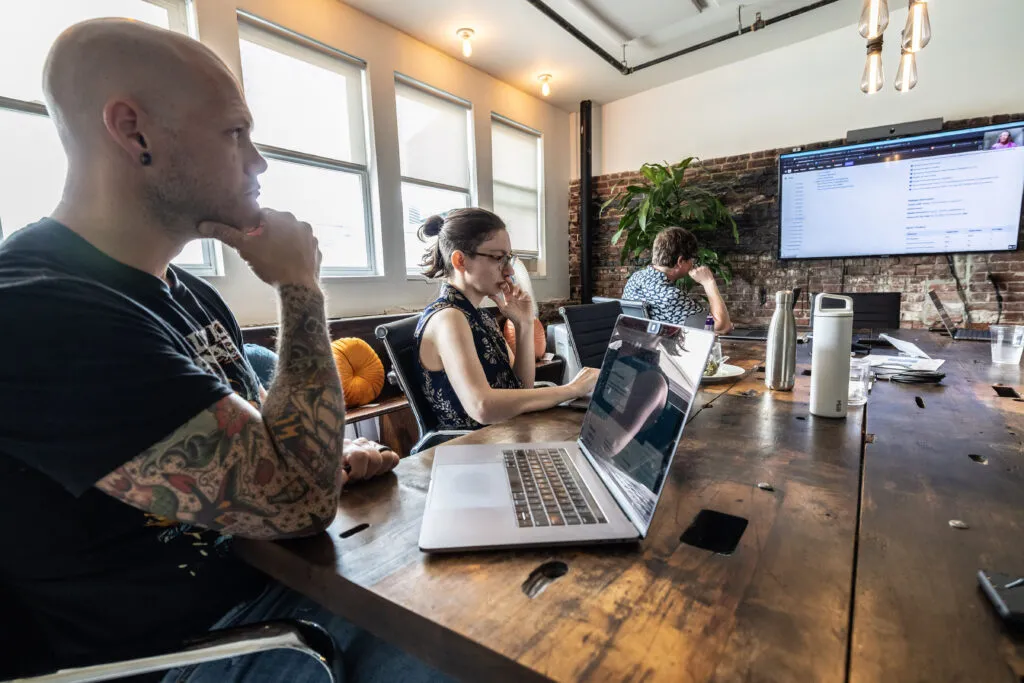 O3 employees at conference table attending a virtual meeting.