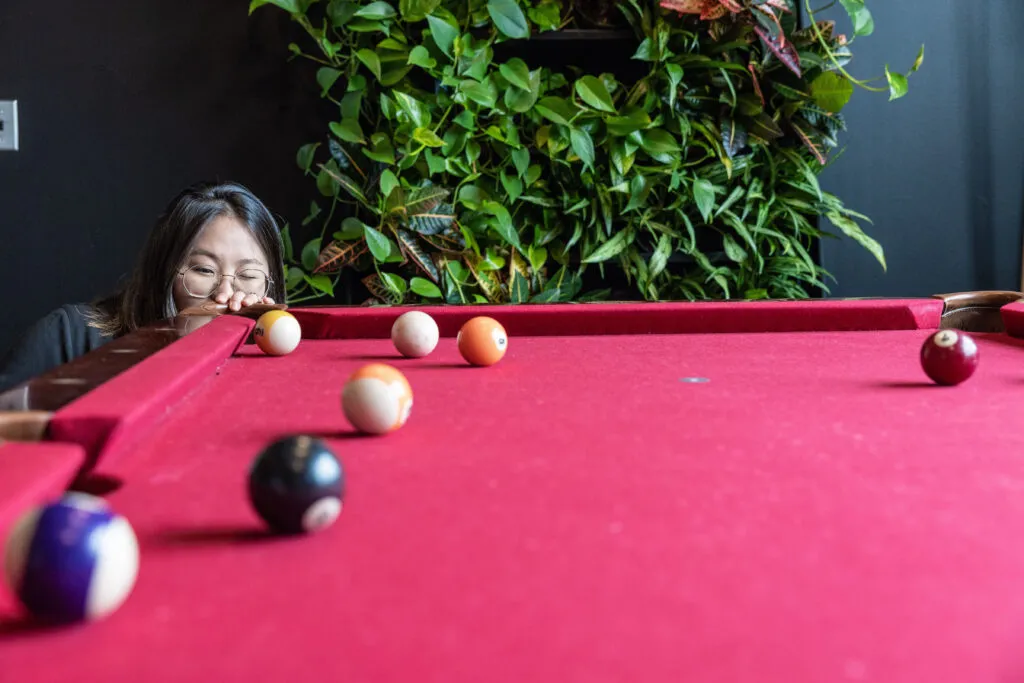 Red pool table with O3 employee lining up a shot.