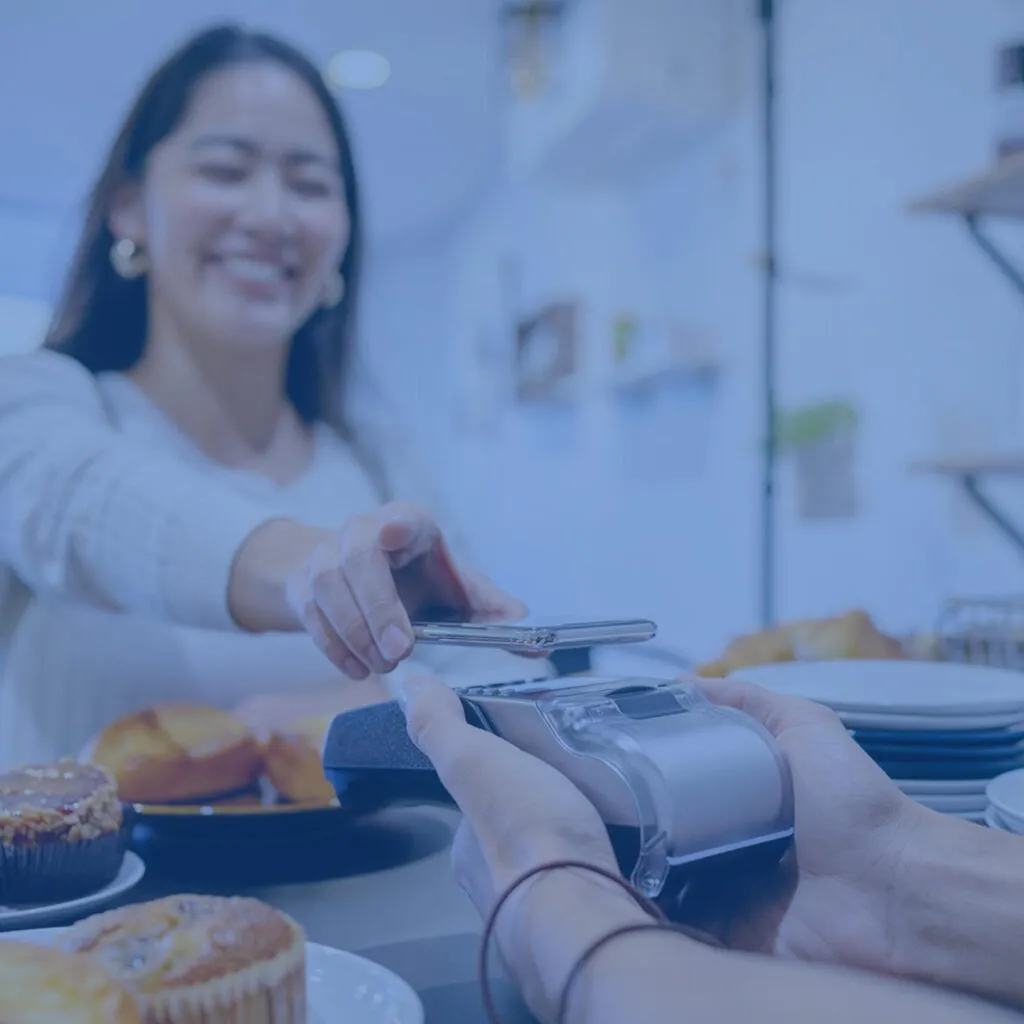Woman at a bakery using her phone at point of sale terminal.